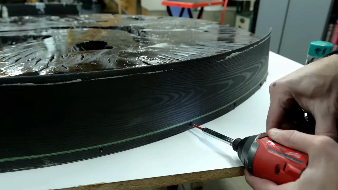 Flexible black landscape edging fastened around the circular slab on a white mold base