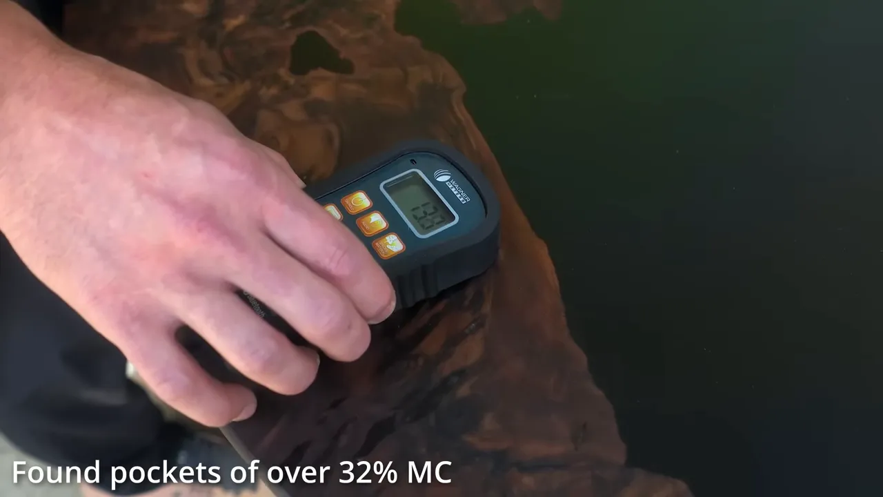 Hand holding a moisture meter against the walnut beside a black epoxy-filled area