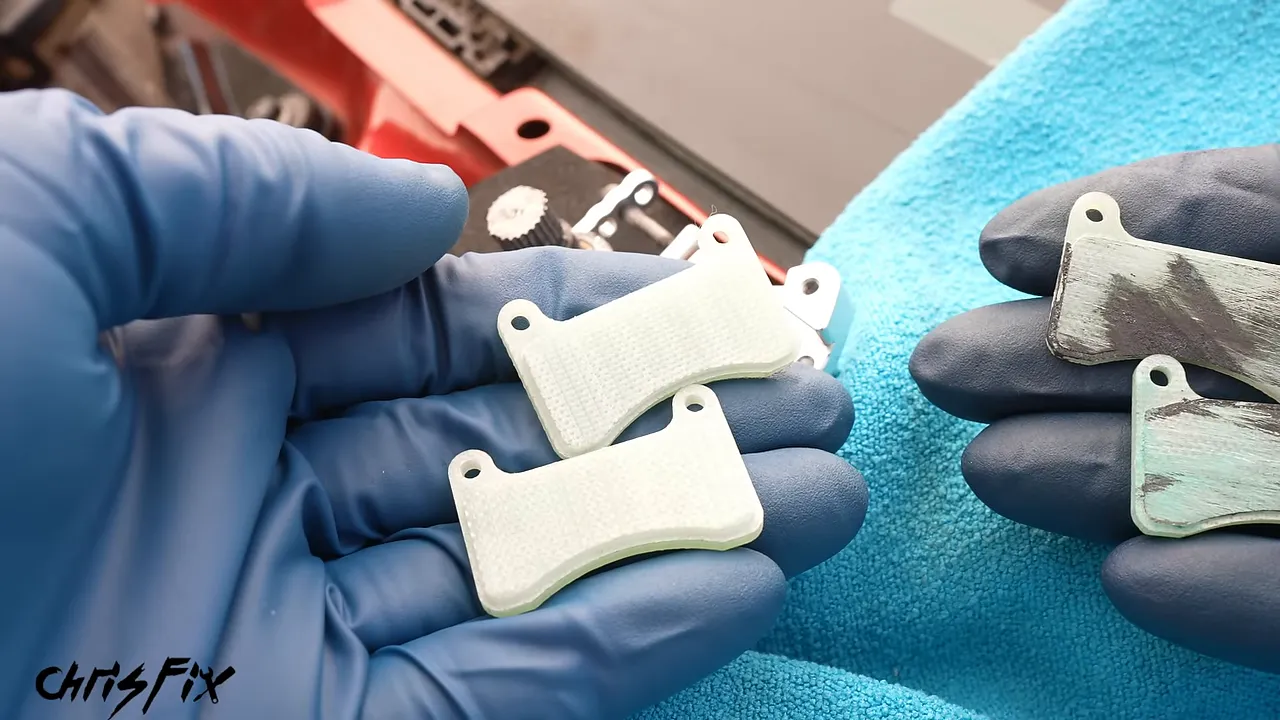 Gloved hands holding two clean miniature pads beside two dark-marked miniature pads