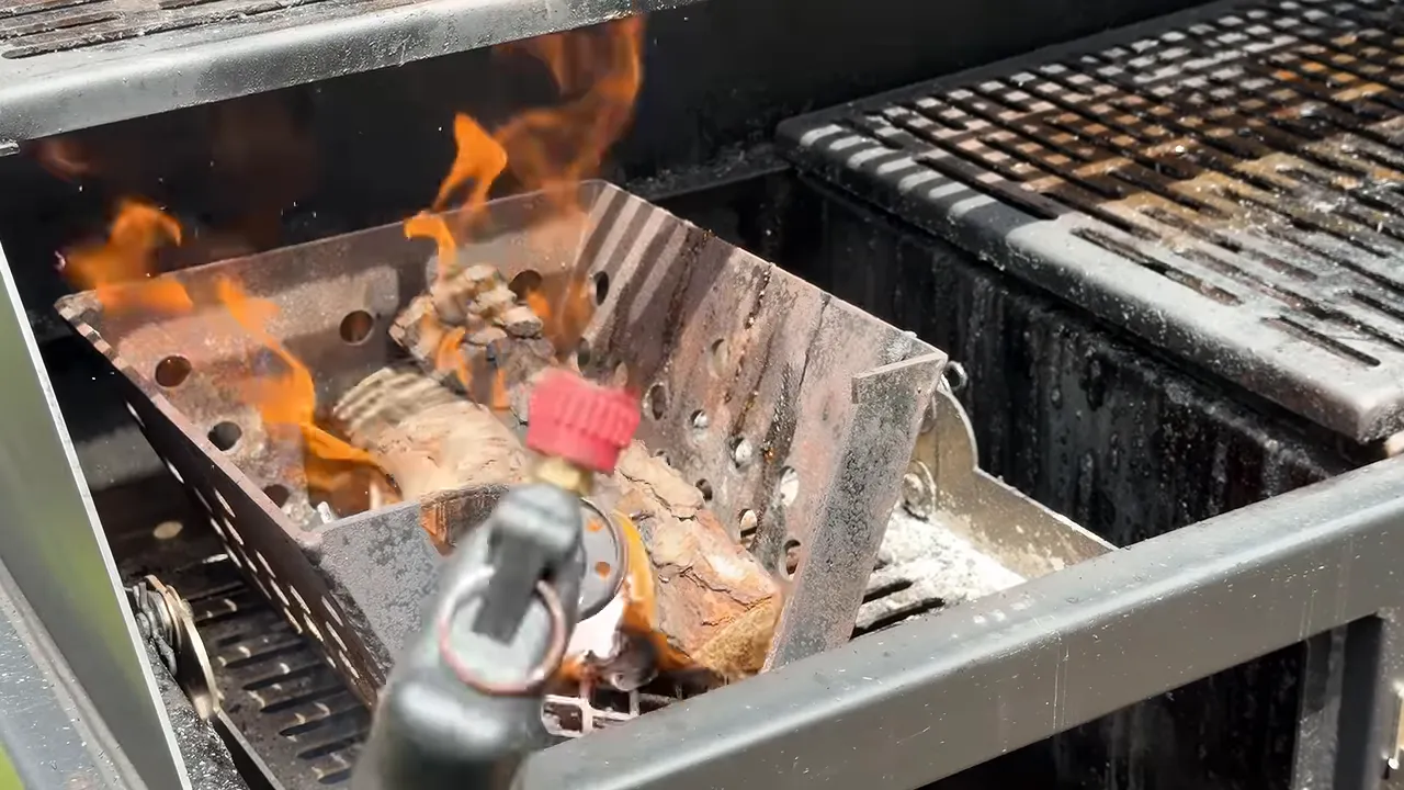 Wood splits burning over charcoal inside the smoker's metal fire basket