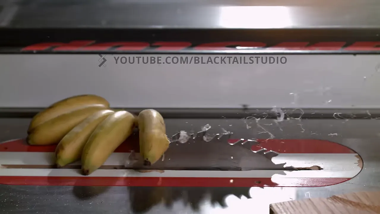 Bananas crossing an exposed table saw blade with pieces and liquid scattering