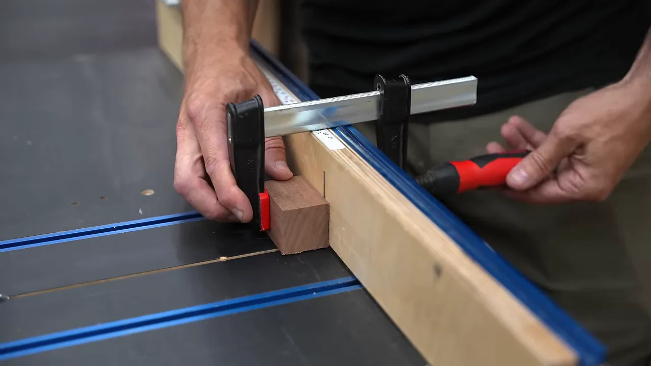 Small wood block secured with a clamp against the fence of a table saw crosscut sled