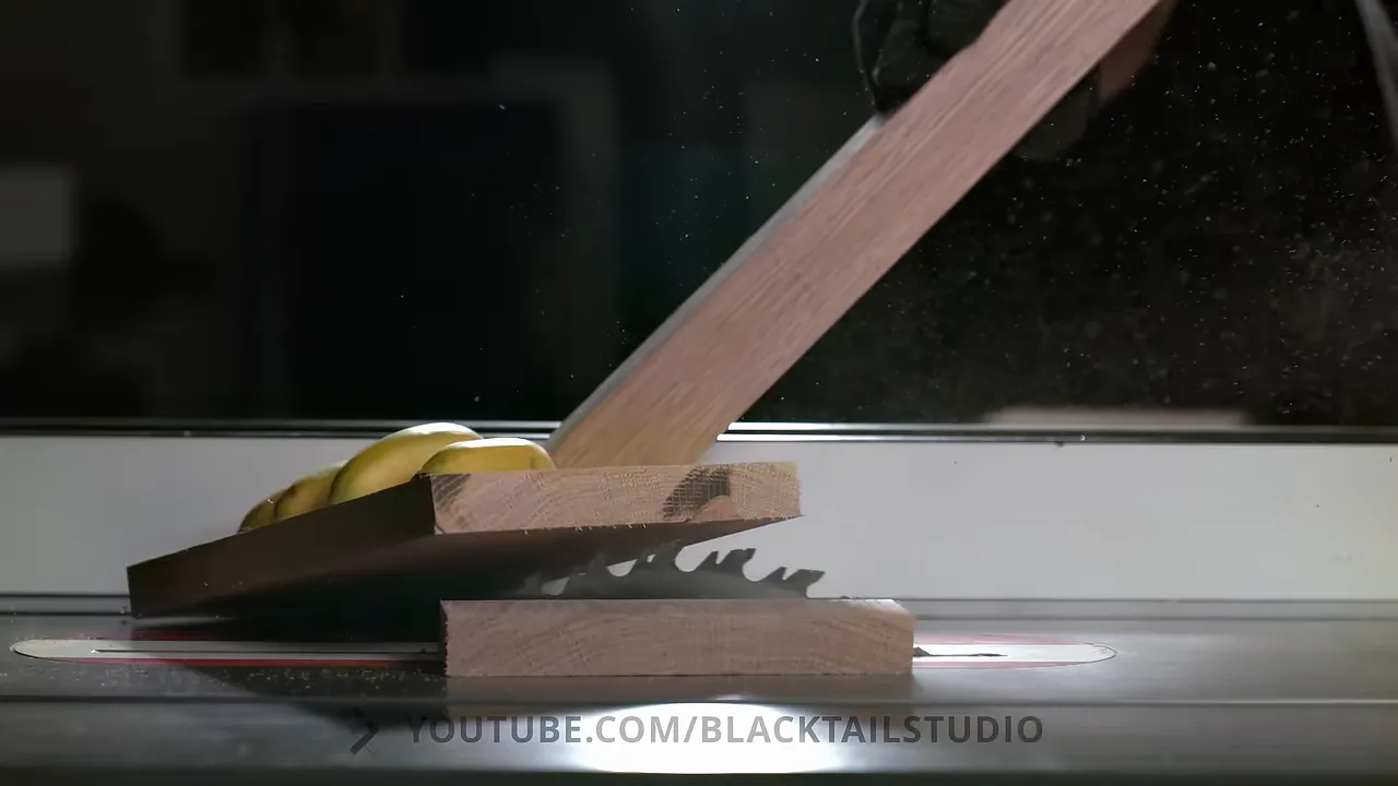 Board carrying bananas lifting above the table saw blade beneath a wooden push stick