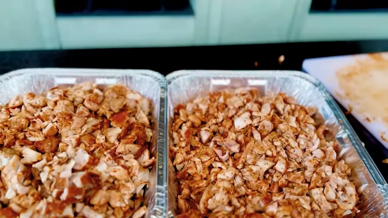 Two foil pans filled with chopped chicken thigh meat