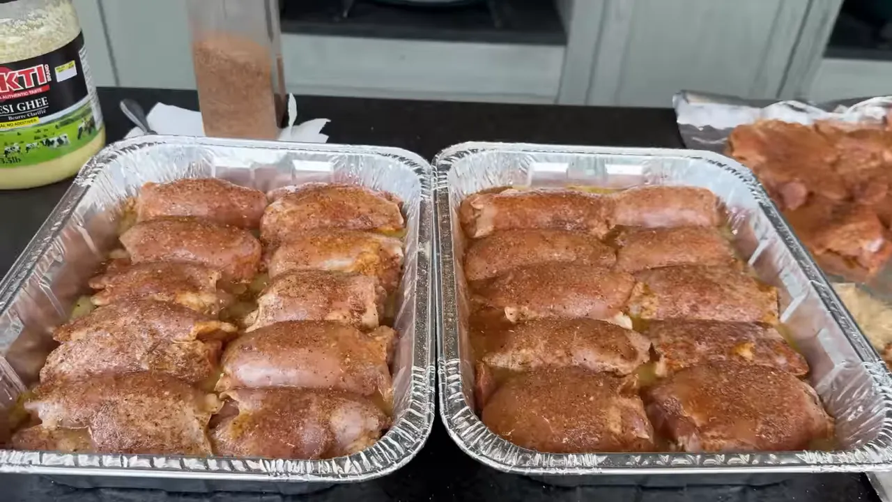 Rolled seasoned chicken thighs arranged snugly in two foil pans