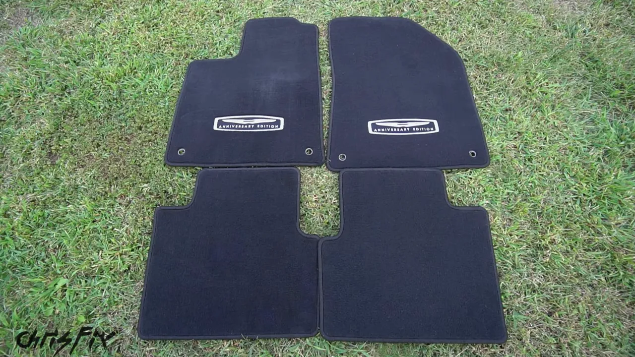 Four clean black carpeted floor mats arranged on grass