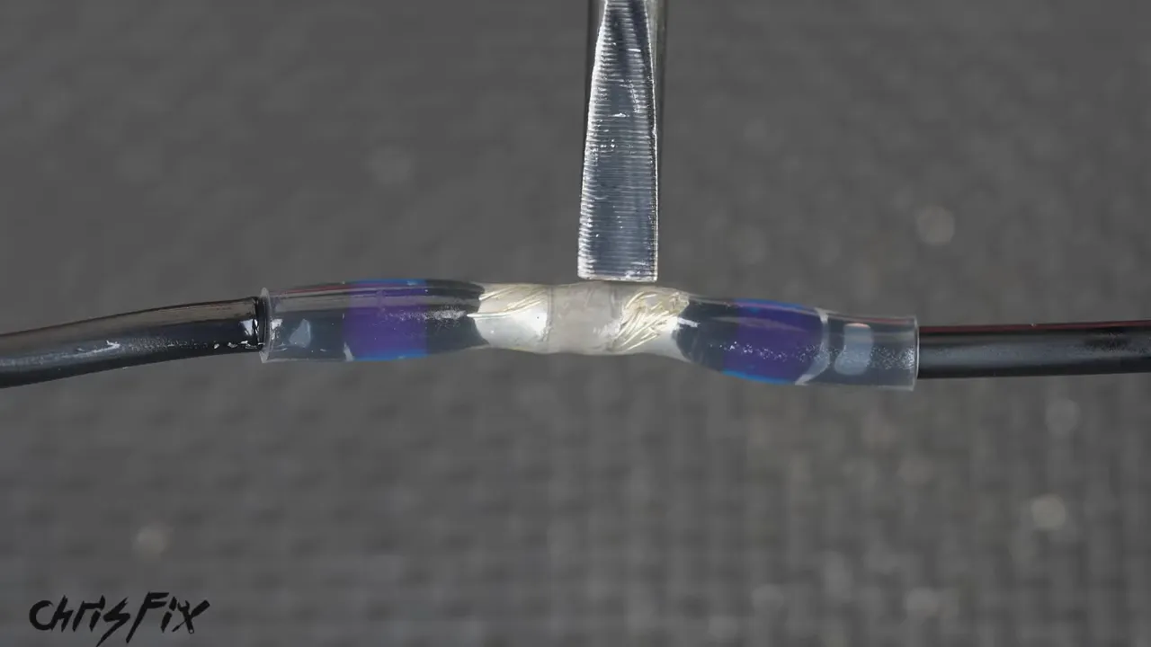Close-up of a finished wire splice inside a clear sleeve with blue sealing rings