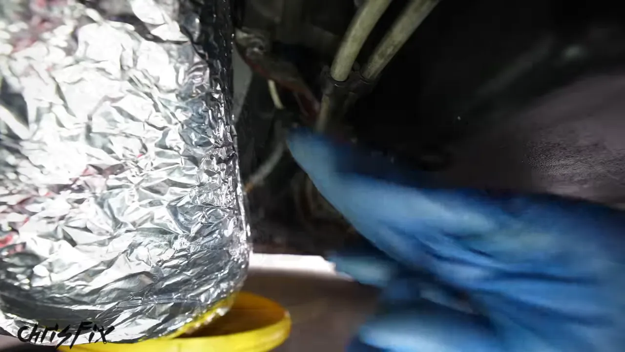 Aluminum foil covering a wrapped exhaust section beside the engine oil pan and yellow drain pan