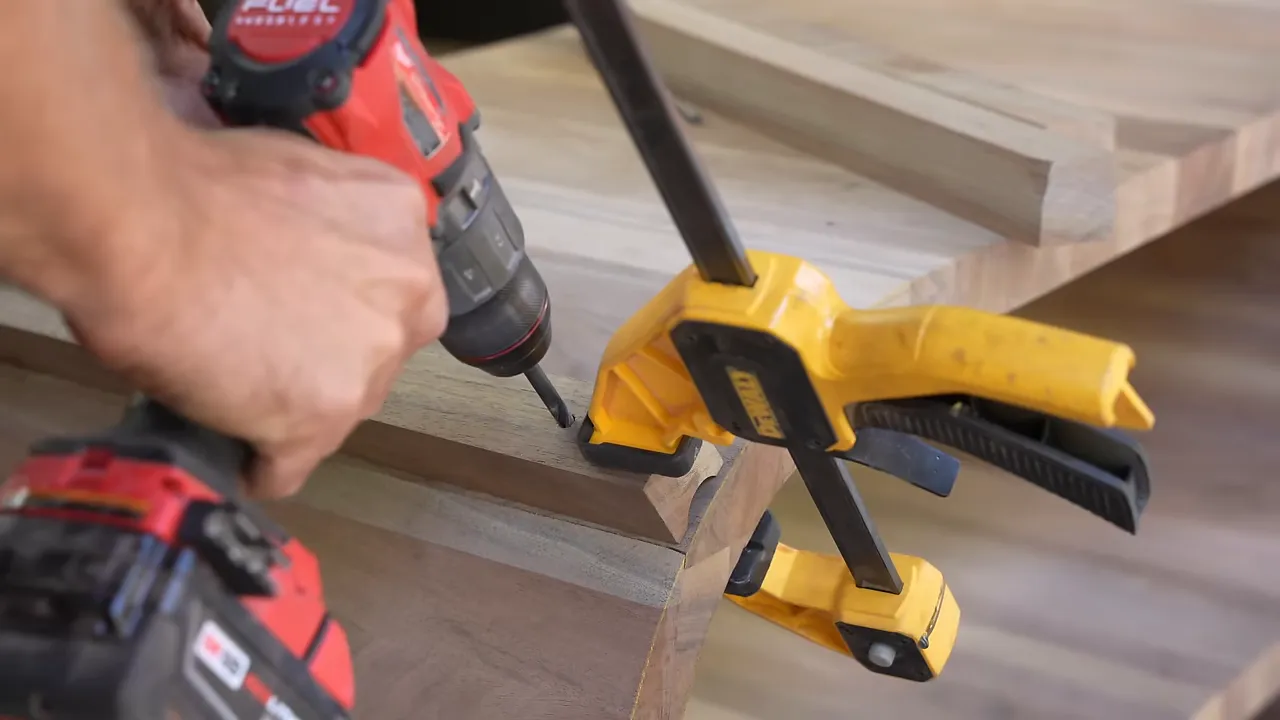Drill operating through a wooden guide clamped to the curved walnut cabinet side