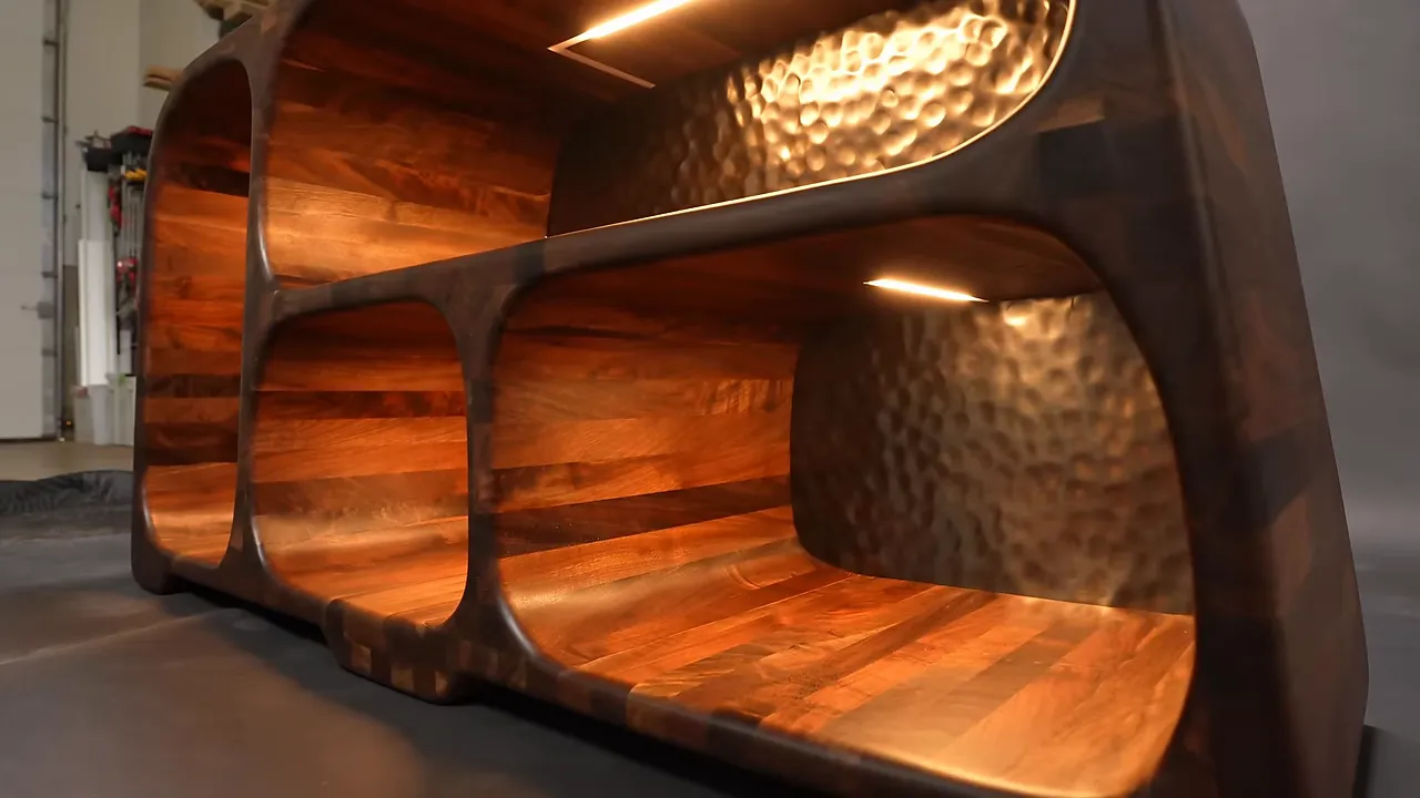 Finished sculpted walnut cabinet with warm interior lighting and hammered metal back panels