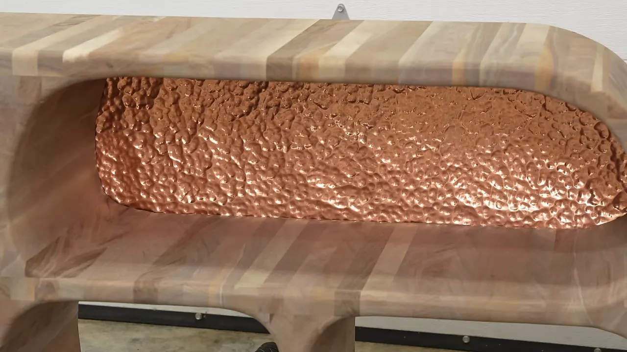 Hammered copper panel behind a wide opening in the unfinished walnut cabinet
