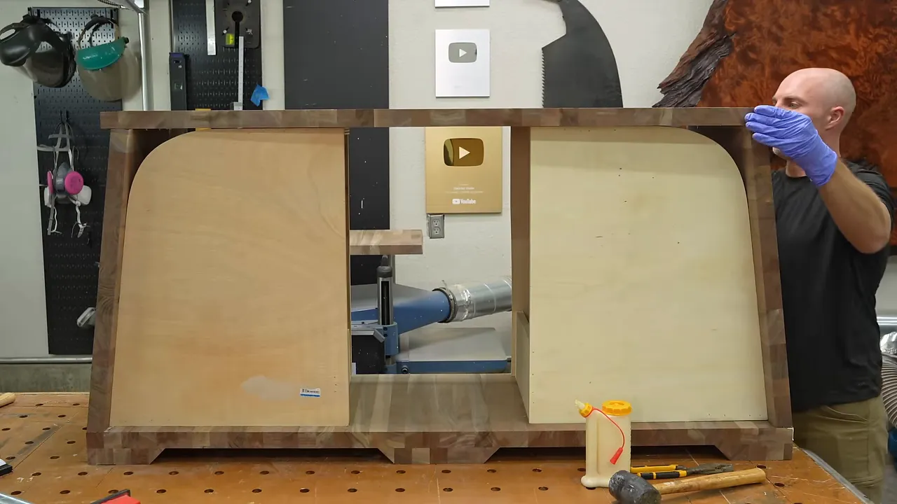 Walnut cabinet assembly surrounding upright plywood templates on a workbench