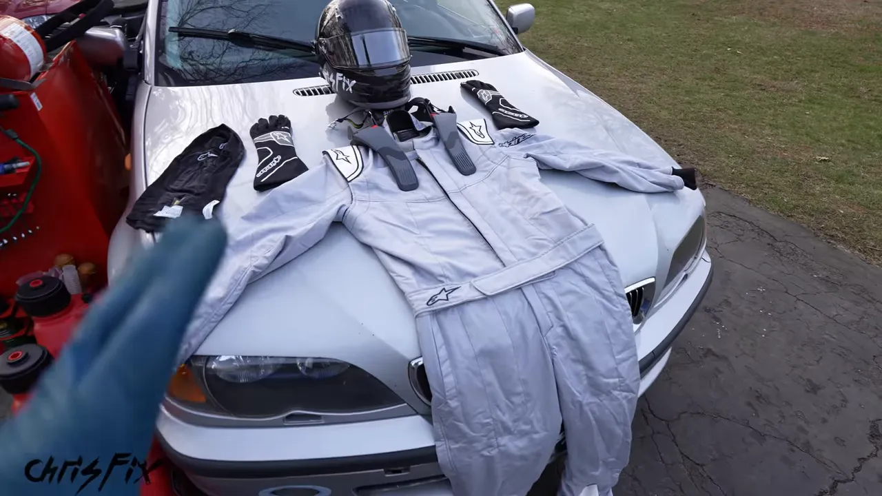 Racing suit, gloves, helmet, balaclava, and head-and-neck restraint arranged on the BMW hood
