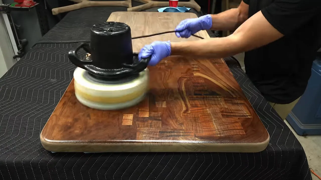 Buffer spreading finish across a walnut desktop with finished dark wood beside unfinished pale wood