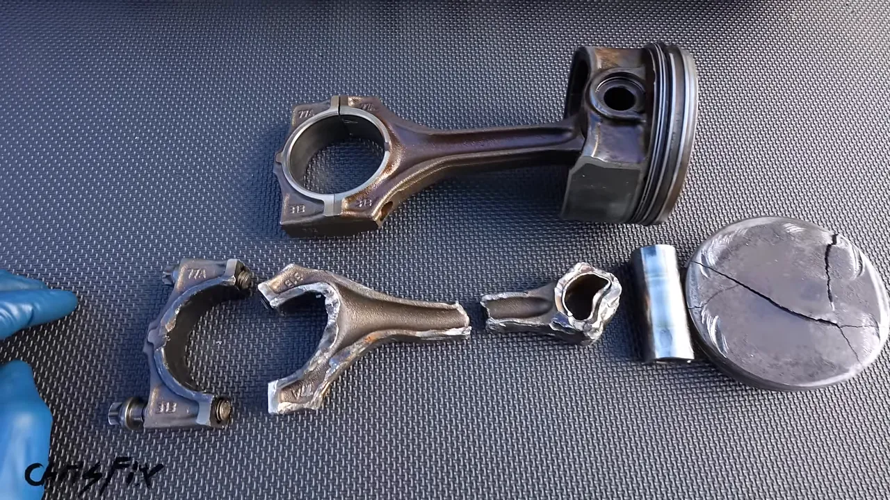 Intact piston and connecting rod above a broken connecting rod and cracked piston crown