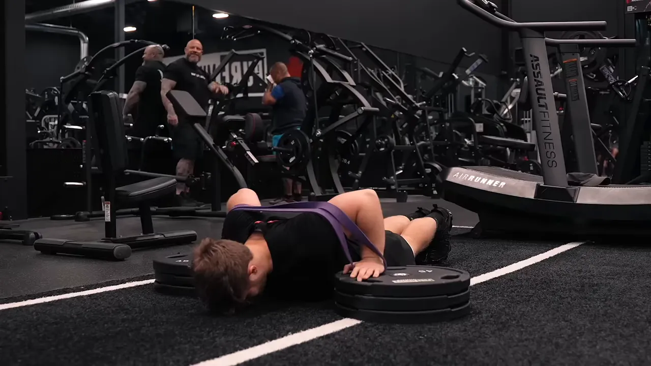 Lifter at the bottom of a push-up with hands elevated on plate stacks and a purple band across his back