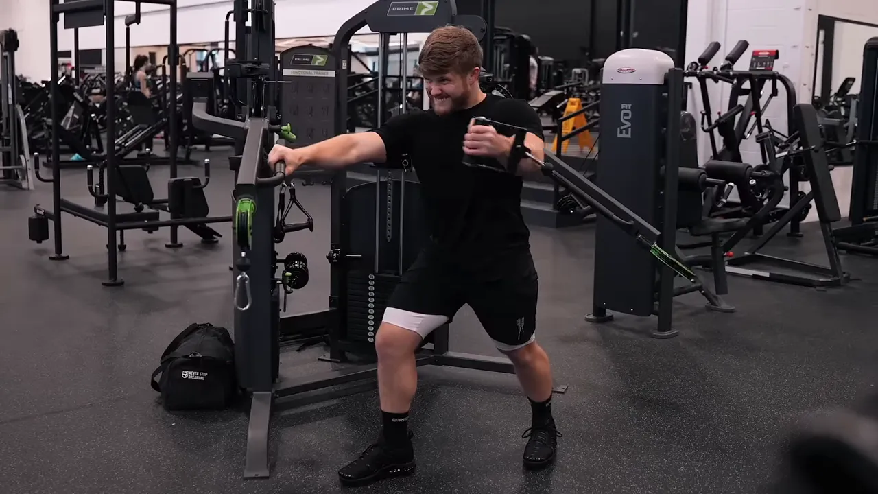 Lifter bringing one cable handle across his chest while bracing his opposite hand against the machine