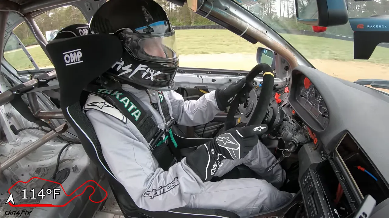 Helmeted driver strapped into the BMW with a cabin temperature overlay reading 115°F