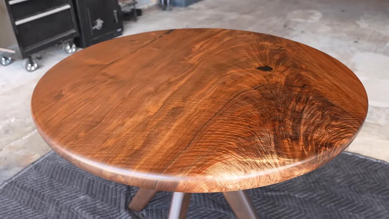 Finished round figured walnut table with curved wooden legs and brass details