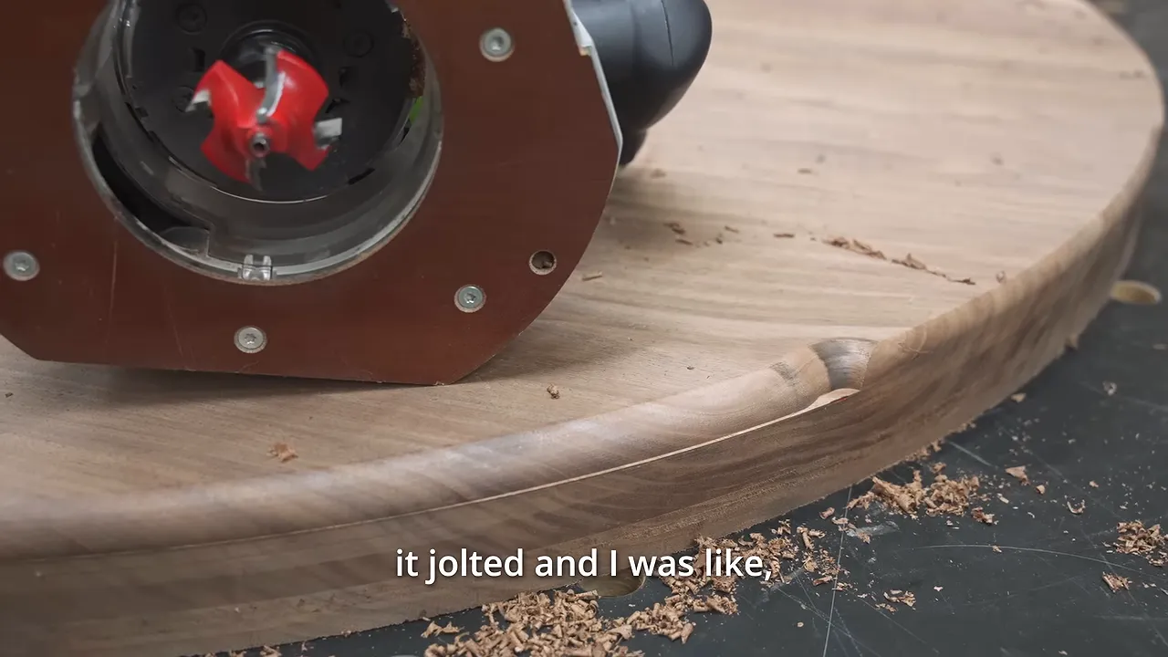 Router resting beside a gouged section of the round walnut tabletop edge