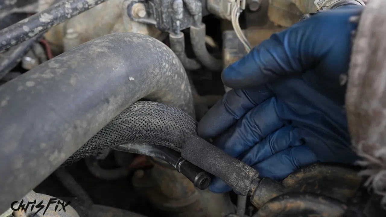 Smoke escaping beside a disconnected vacuum hose near the intake manifold