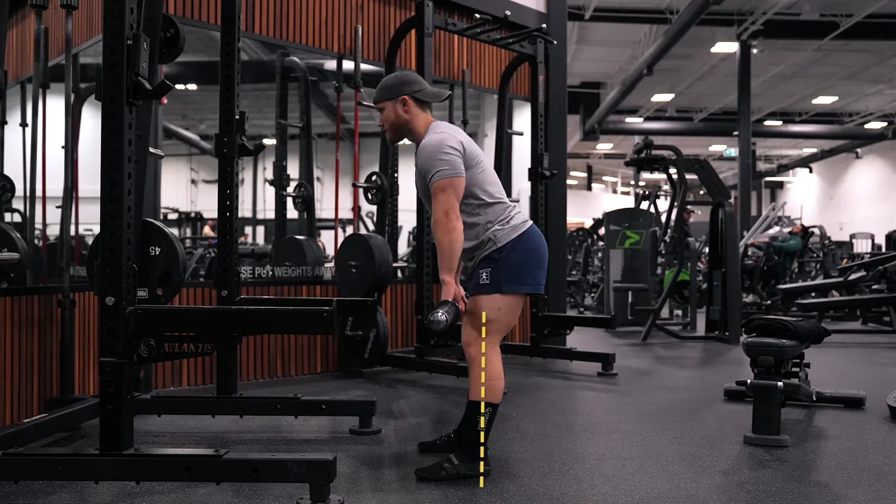 Side view of a Romanian deadlift with the hips pushed back and the bar close to the legs