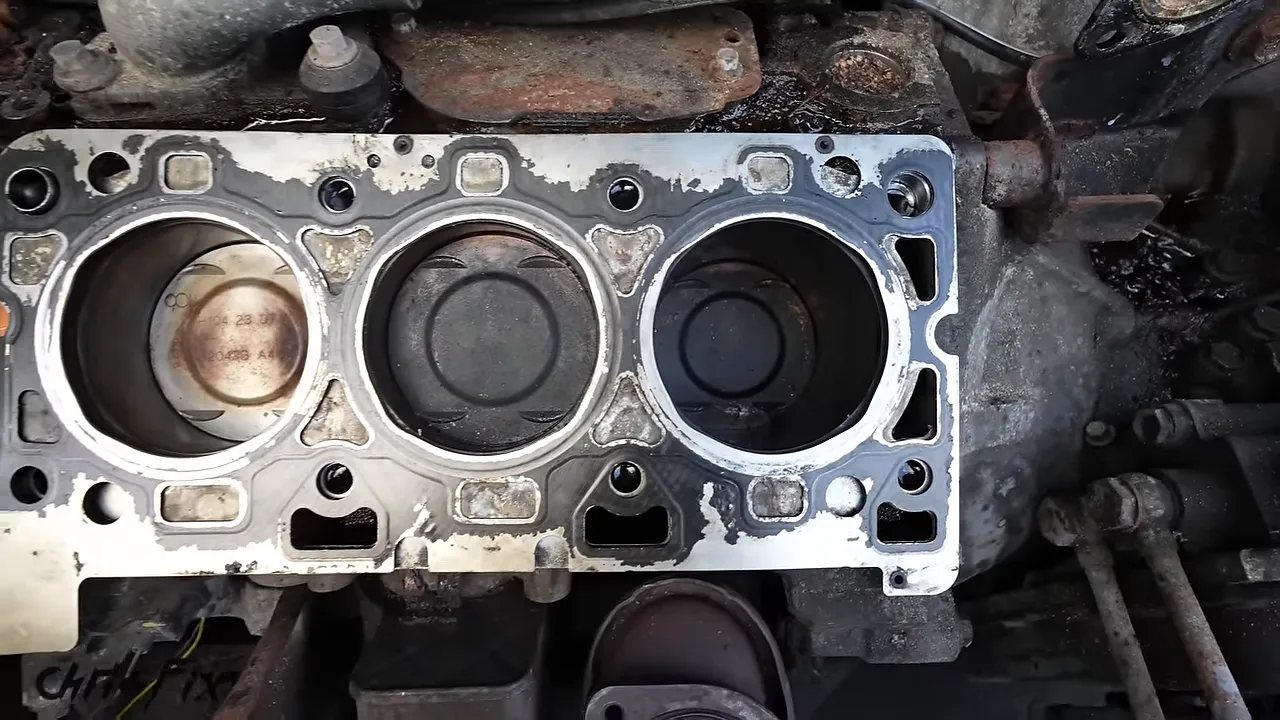 Exposed engine block showing one light-colored piston beside darker piston crowns