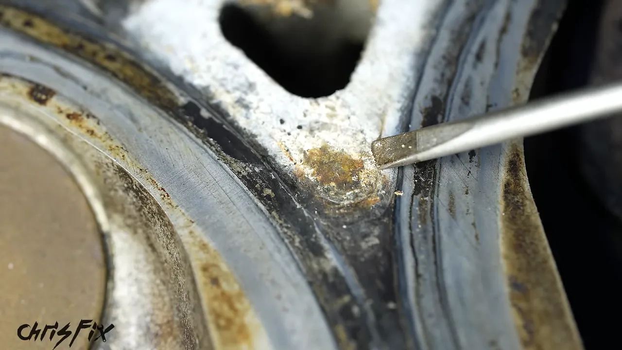 Close-up of pale deposits beside a combustion chamber with a metal pointer indicating the area