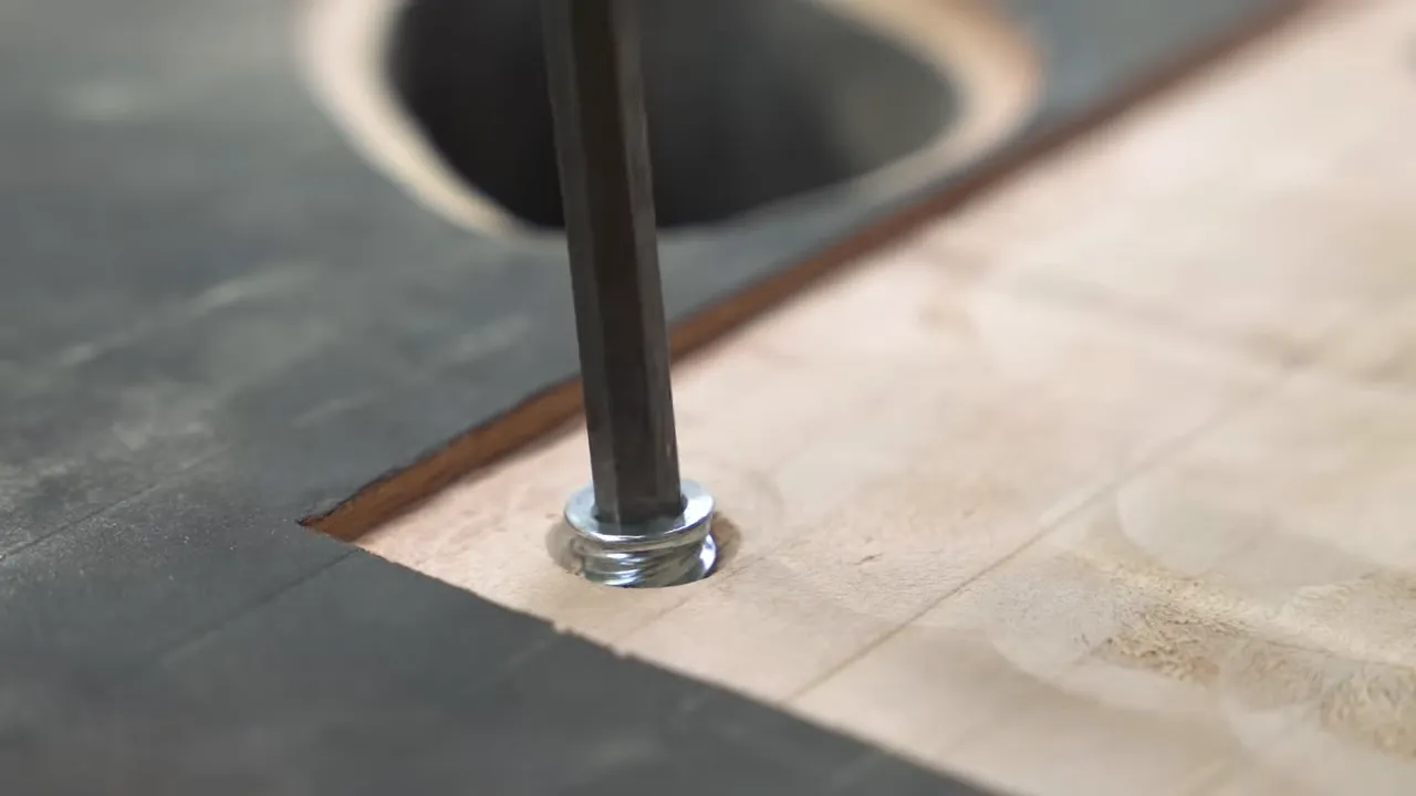 Countersunk fasteners seated in a bronze mounting plate recessed into blackened wood