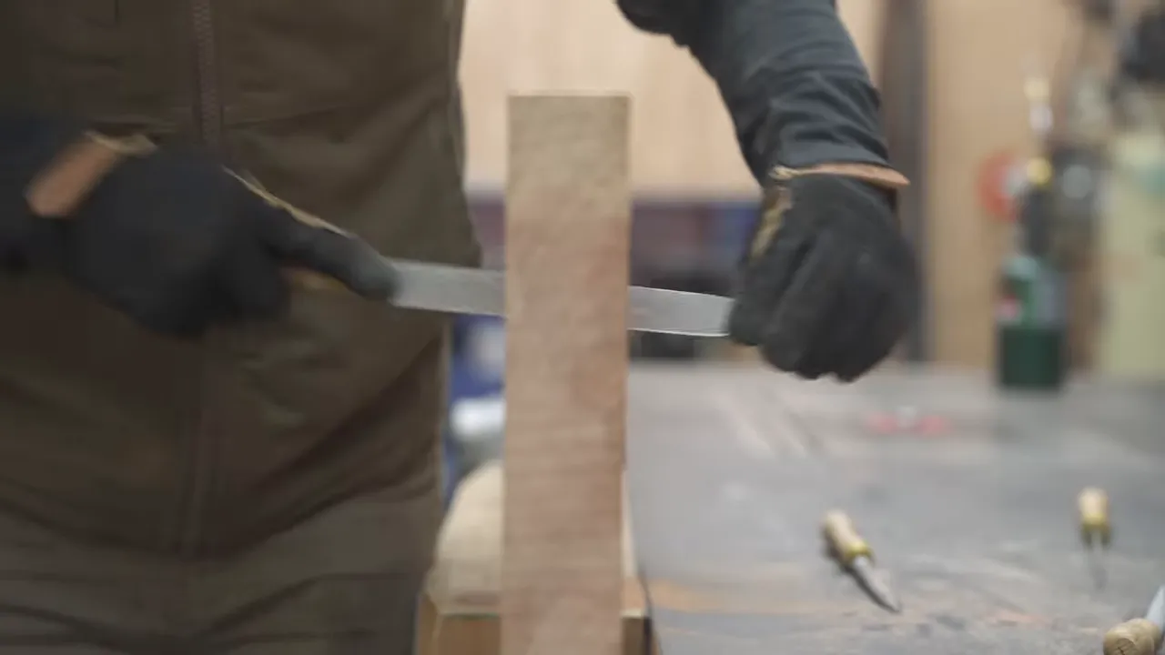 A hand rasp shaping the inside edge of a carved redwood opening