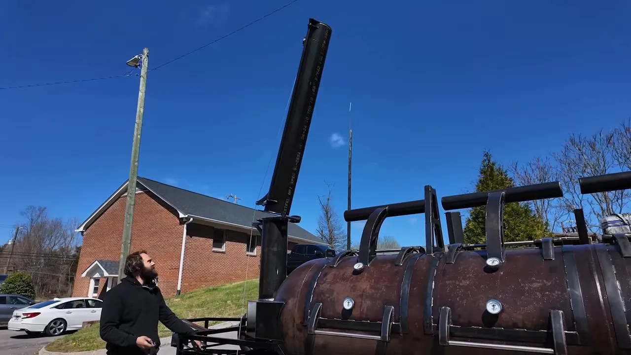Tall hinged smokestack raised nearly upright above a patina tank smoker
