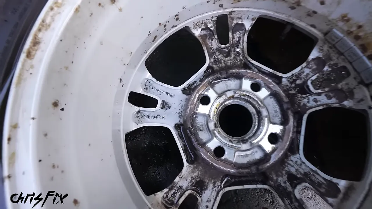 Close-up of the back of a wheel spoke with dark pitted areas beside cleaner silver paint