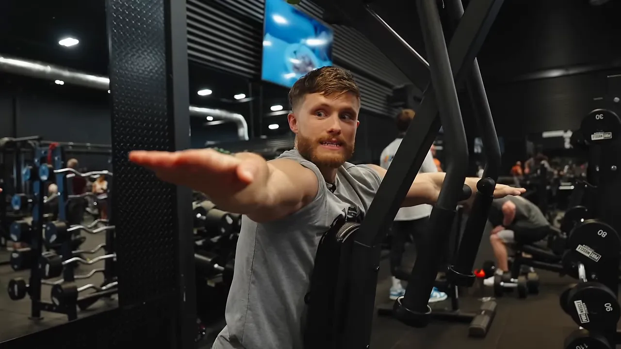 Jeff on a reverse pec deck with his arms extended widely to either side