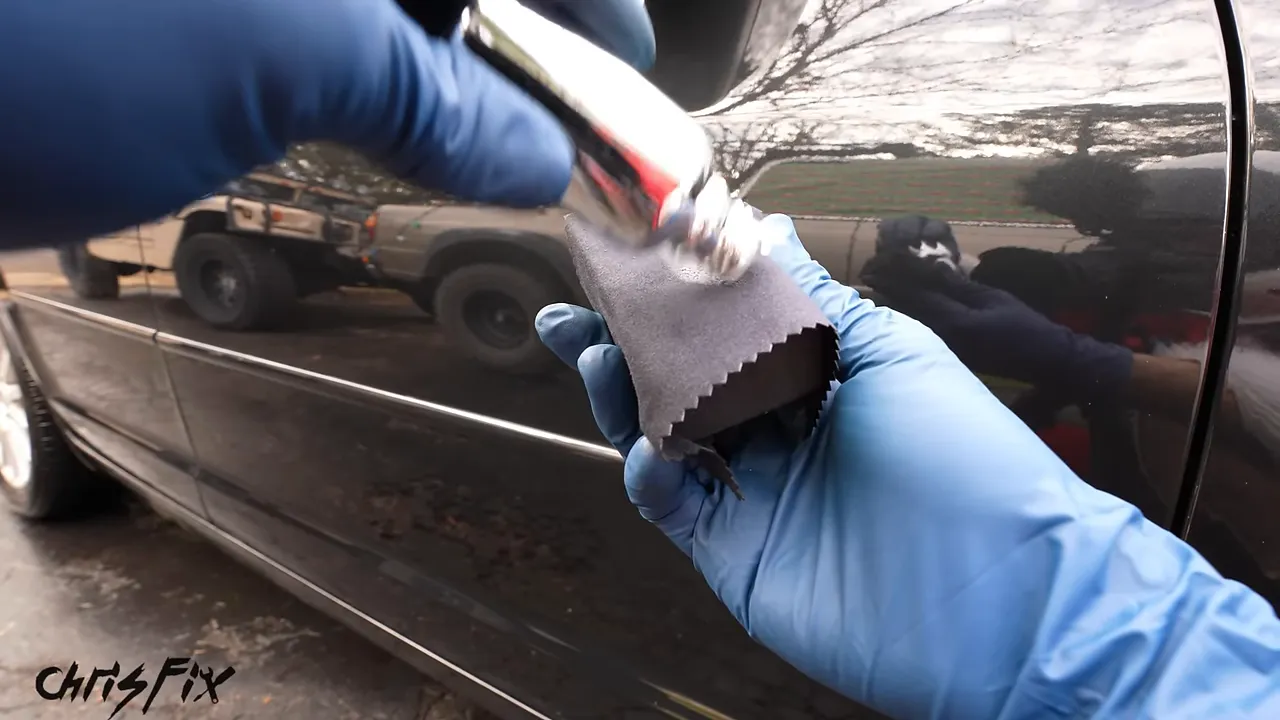 Blue-gloved hands applying drops from a bottle onto a cloth-wrapped applicator sponge