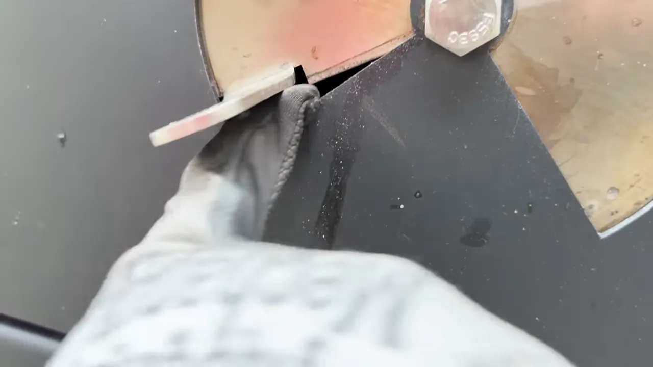 Gloved thumb beside the narrow opening of the grill's lower intake vent