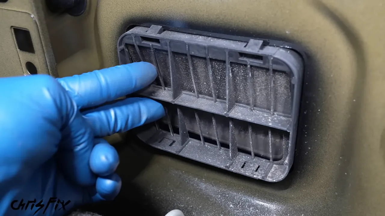 Gloved fingers lifting a flap on a trunk-mounted pressure-relief vent