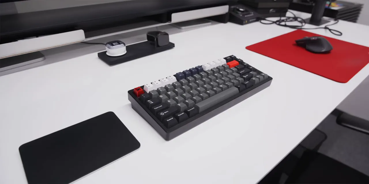 Magic Trackpad to the left of a compact keyboard and a mouse on a red pad to the right