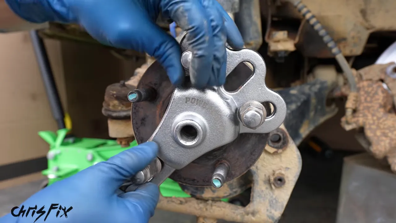 Hub puller plate secured to wheel studs with a slide hammer shaft attached