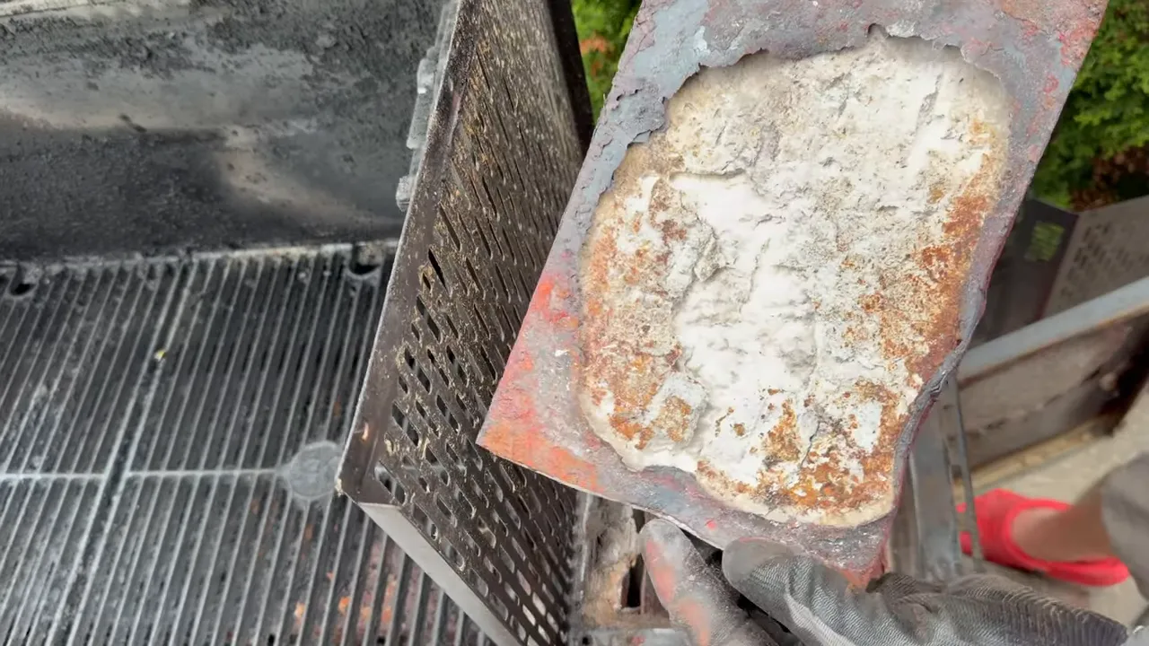 Removed firebox panel with deteriorated metal and exposed pale insulation