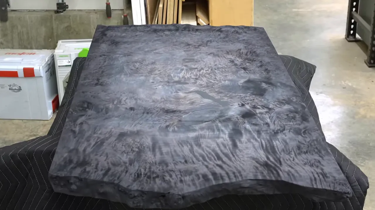 Burl desktop with black edges and a lighter gray center resting in the workshop