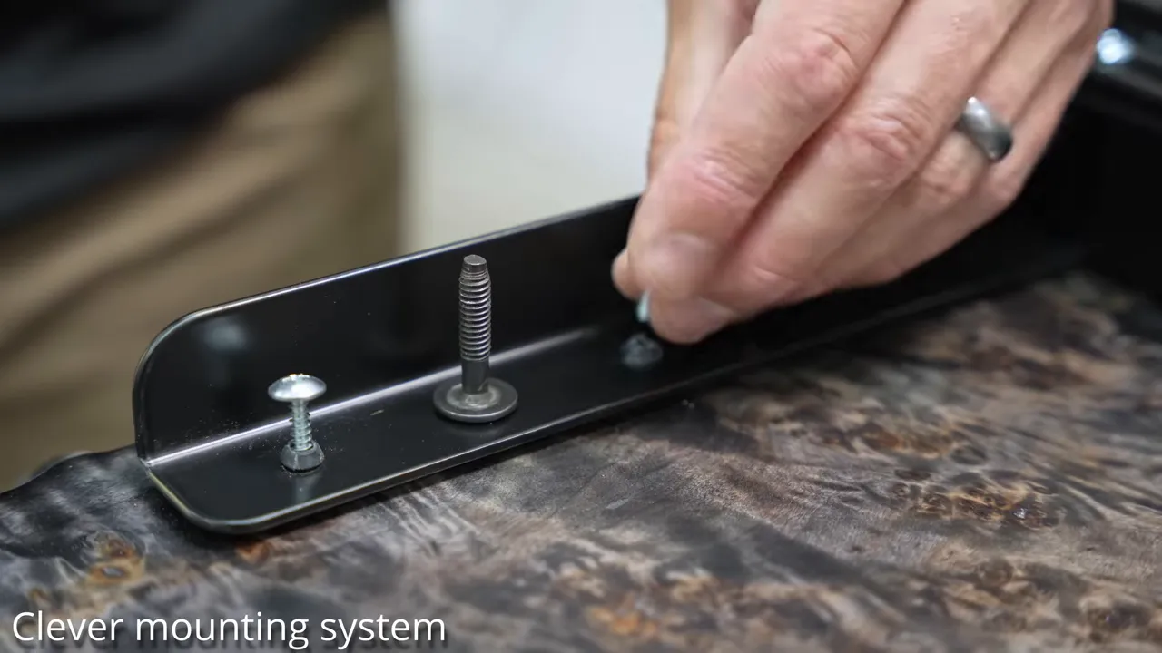 Close-up of the desk base mounting rail with fasteners and rubber bushings against the slab underside