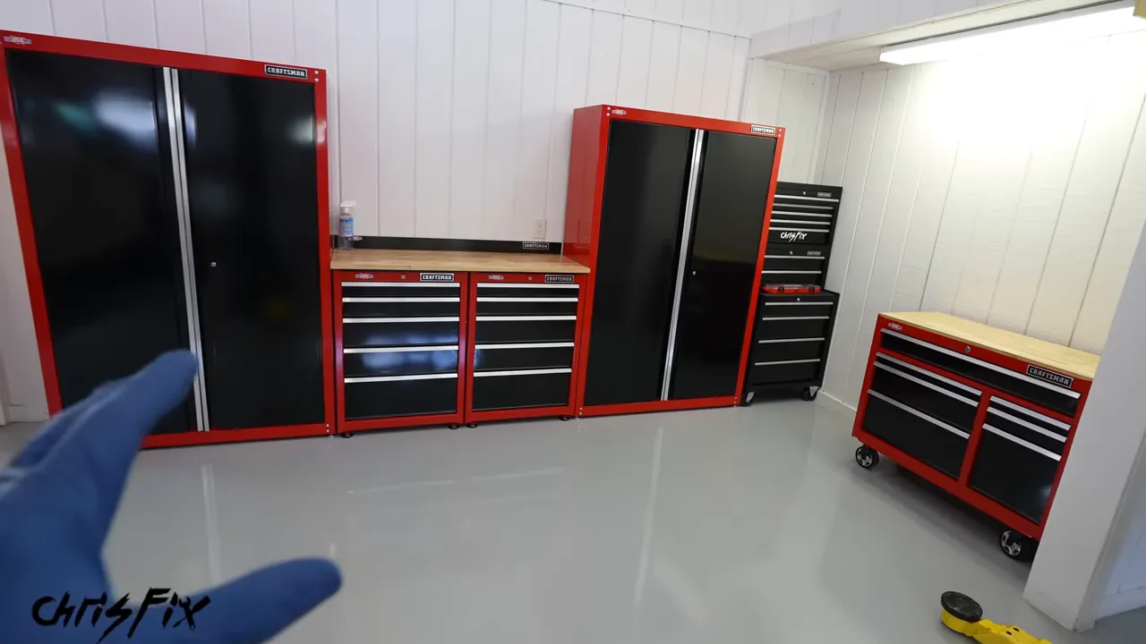 Garage with red and black storage cabinets, rolling toolboxes, and wood work surfaces