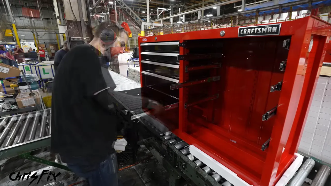 Worker installing a lower drawer into the left side of a red toolbox cabinet
