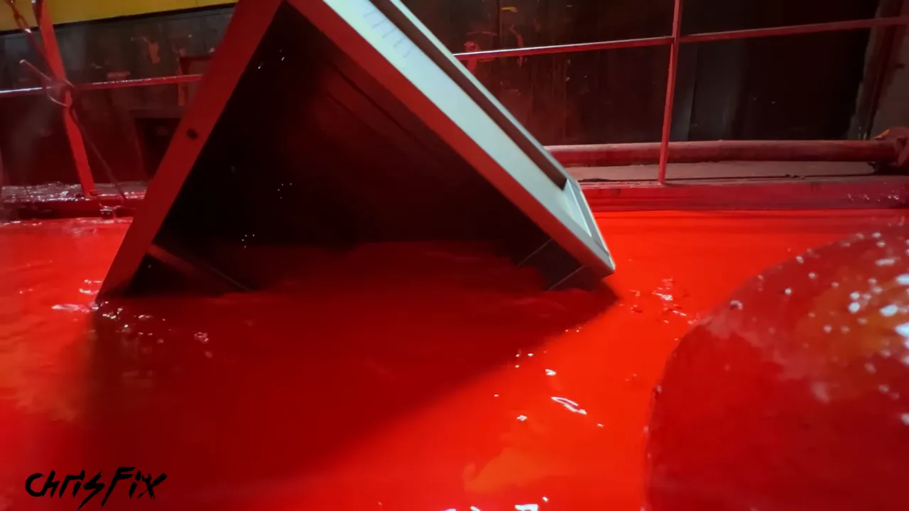 Toolbox cabinet partially submerged at an angle in a red paint bath