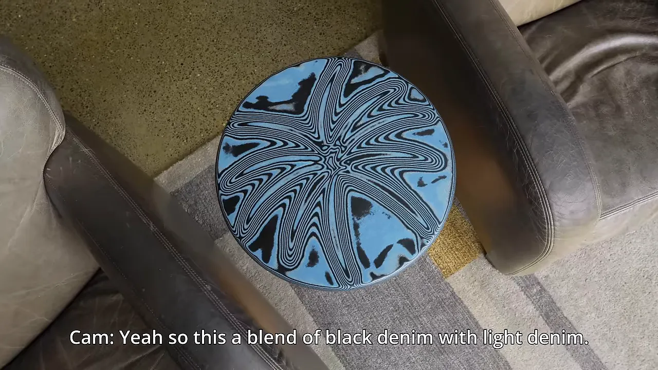 A round blue and black starburst-patterned tabletop between two upholstered chairs