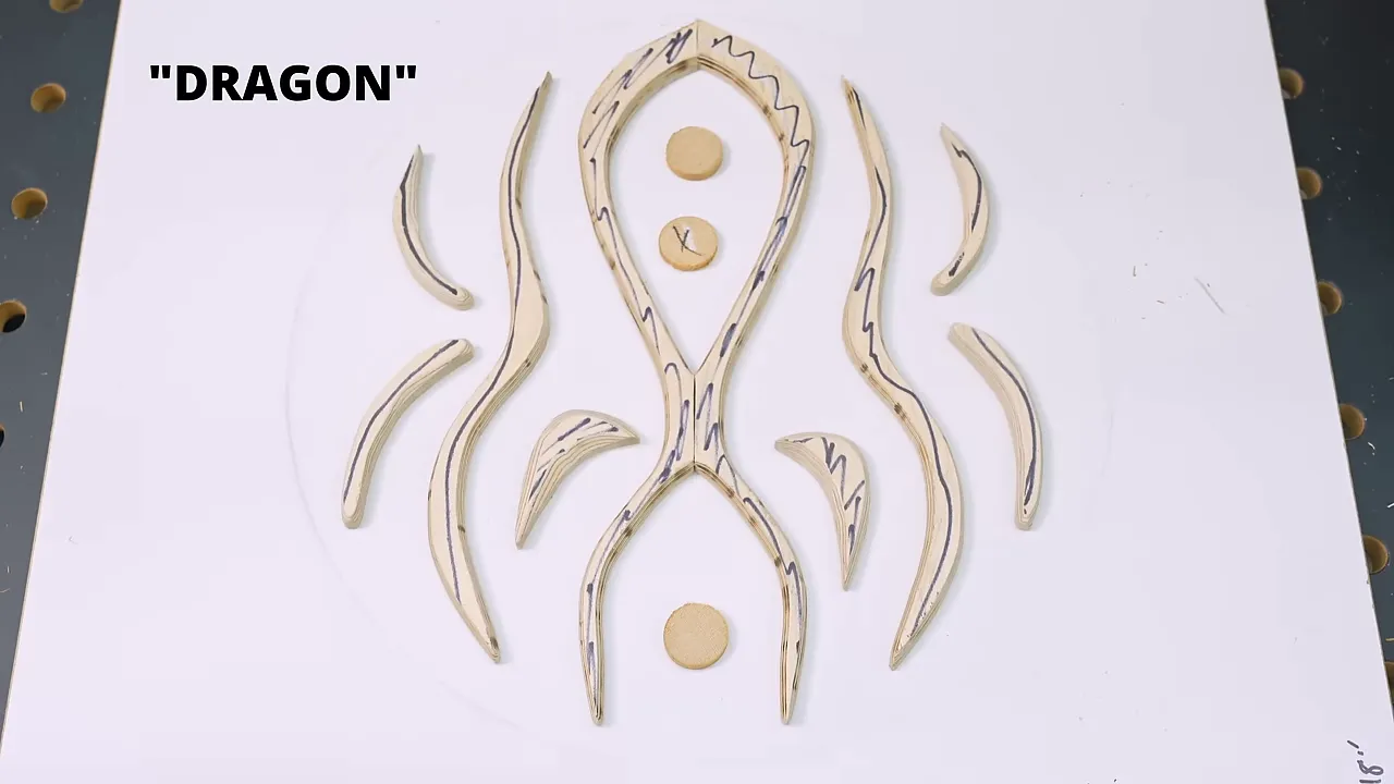 Curved plywood pieces arranged symmetrically on a white board labeled Dragon