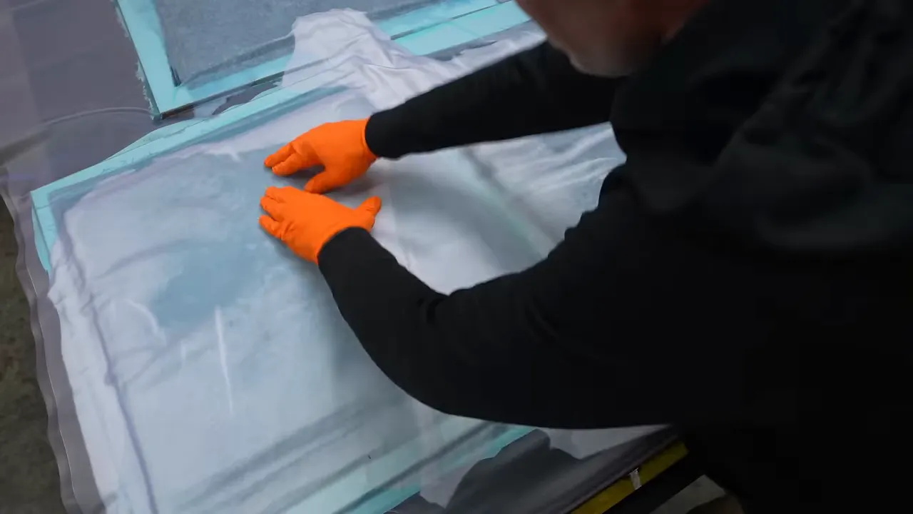 Hands pressing vacuum bag film around several covered rectangular panels