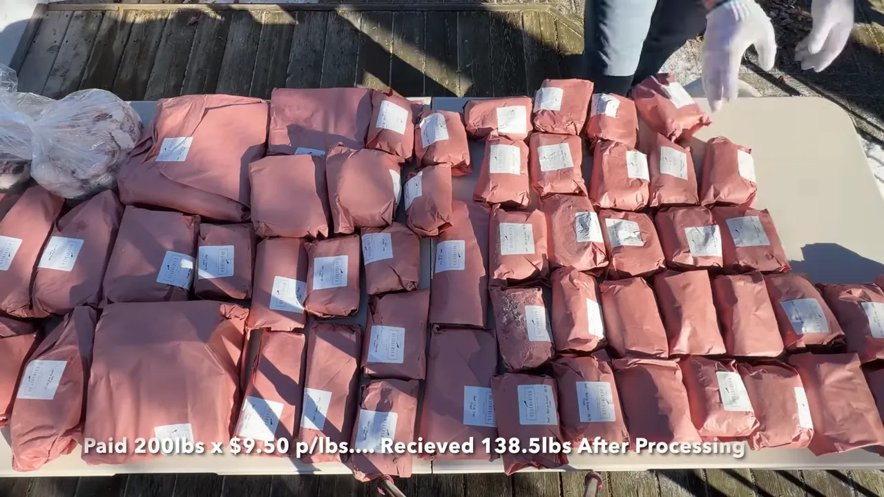 Paper-wrapped beef packages and clear bags spread across an outdoor folding table