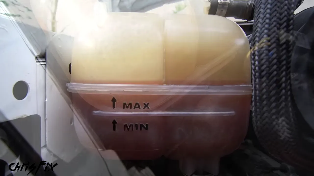 Close-up of a coolant reservoir with visible MAX and MIN markings and red coolant inside
