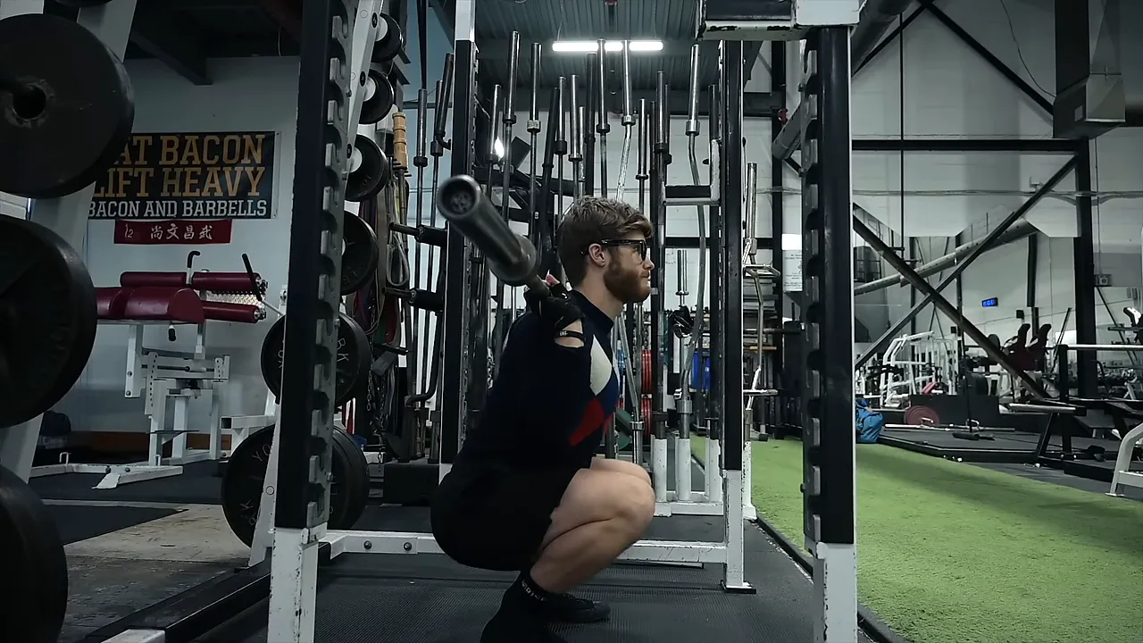 Lifter near the bottom of a barbell squat inside a rack